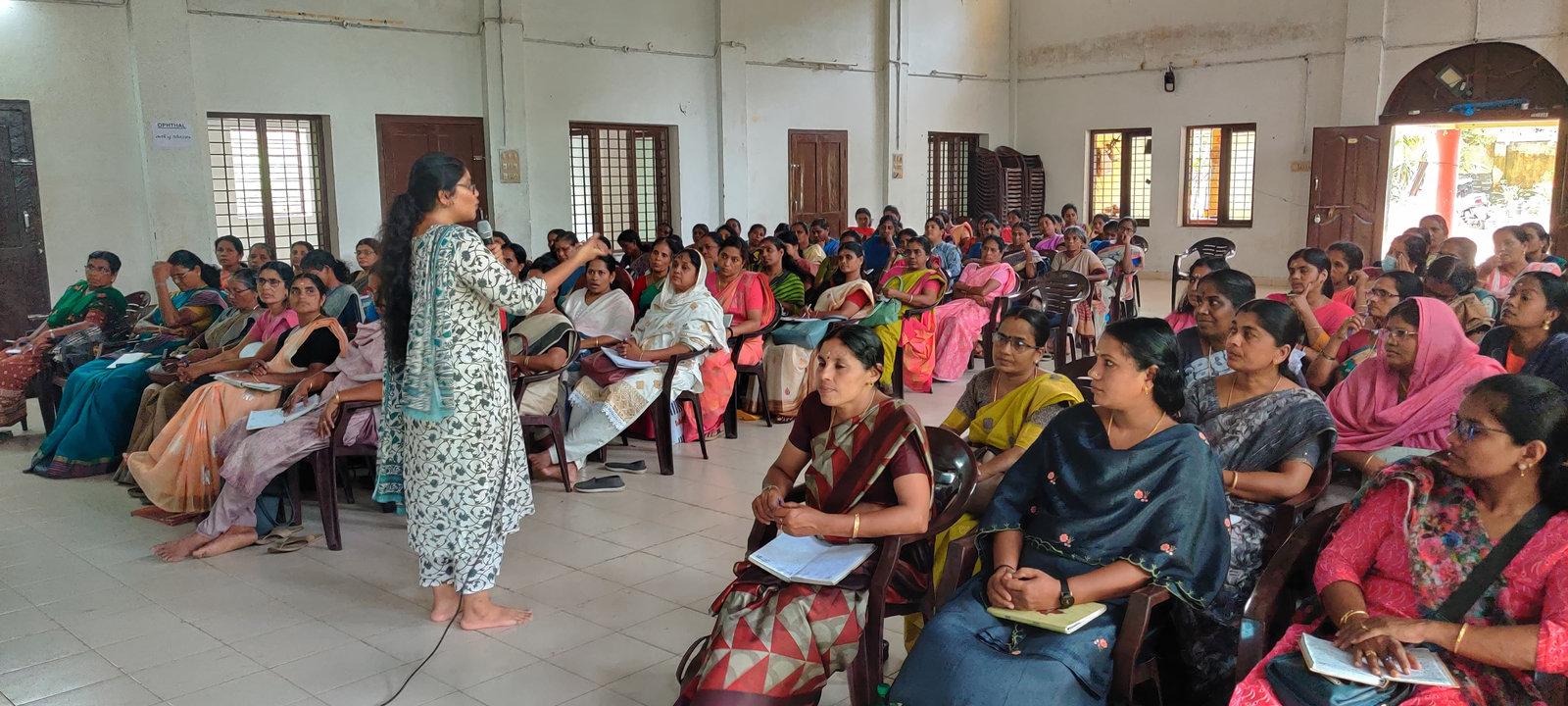 A trainer speaks to Anganwadi teachers in a hall