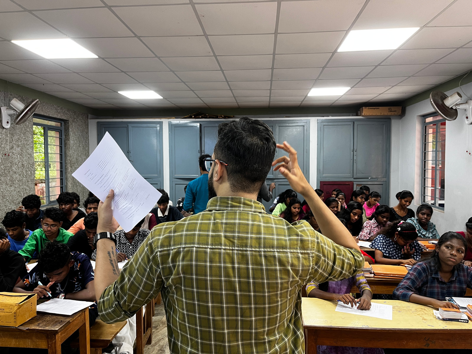A researcher hands out survey sheets to students