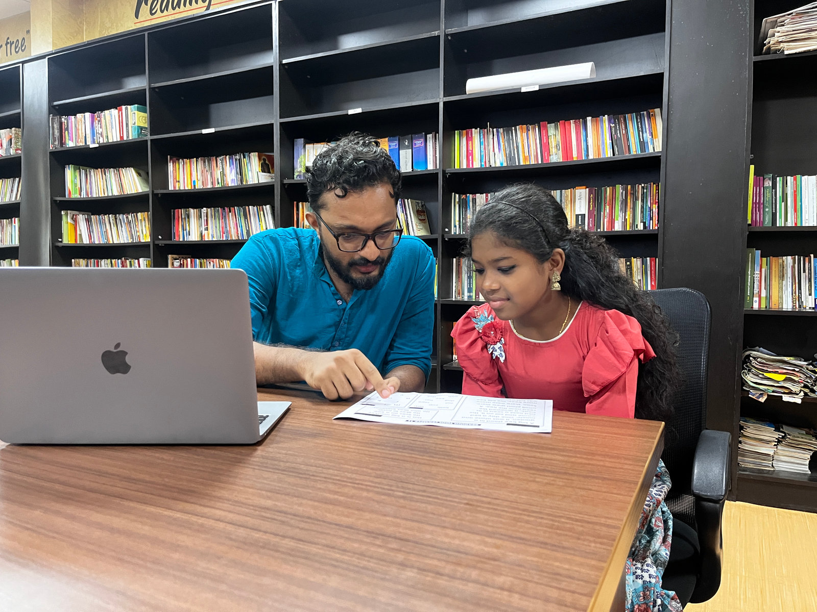 An NPoC researcher works through a reading test with a student in the school library